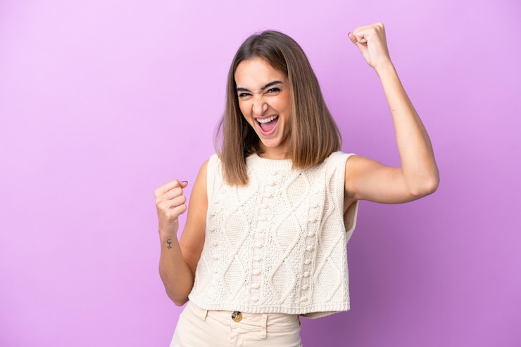 Foto mujer caucásica joven aislada sobre fondo púrpura celebrando una victoria