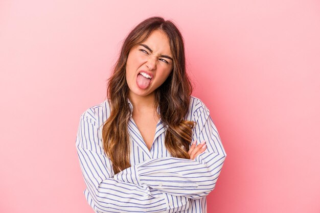 Mujer caucásica joven aislada sobre fondo rosa divertida y amigable sacando la lengua.