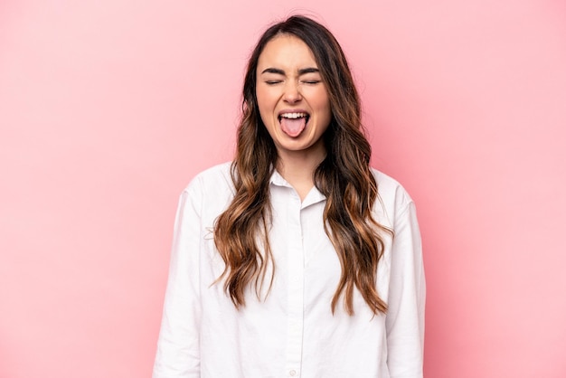 Mujer caucásica joven aislada sobre fondo rosa divertida y amigable sacando la lengua