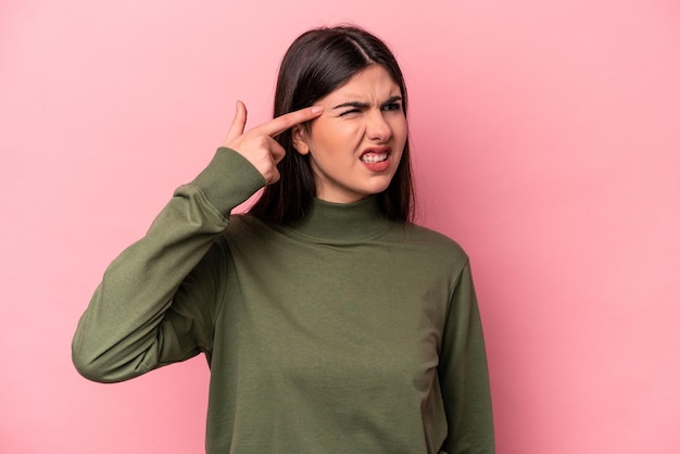 Mujer caucásica joven aislada sobre fondo rosa que cubre las orejas con las manos