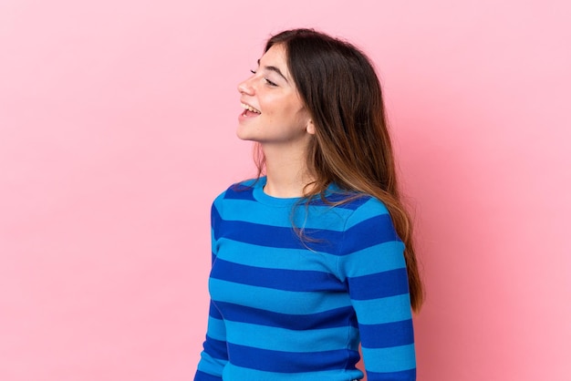 Foto mujer caucásica joven aislada sobre fondo rosa riendo en posición lateral