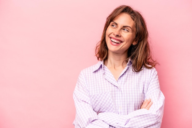 Foto mujer caucásica joven aislada sobre fondo rosa sonriendo confiada con los brazos cruzados