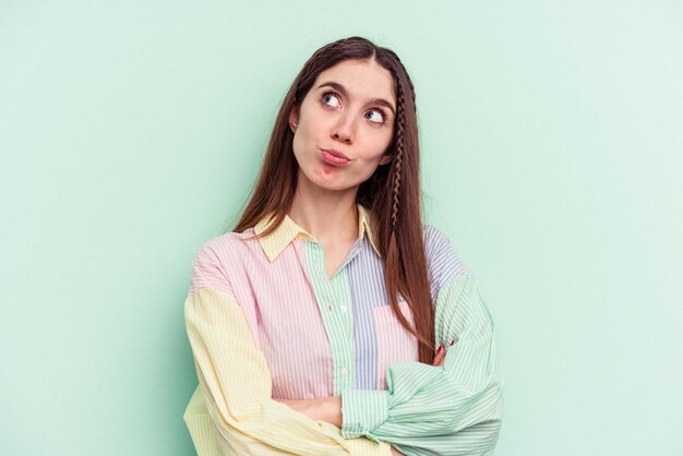 Mujer caucásica joven aislada sobre fondo verde soñando con lograr objetivos y propósitos