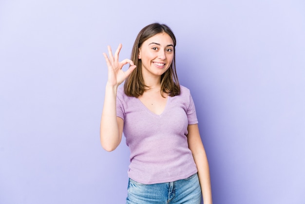 Mujer caucásica joven alegre y confiada que muestra el gesto aceptable.