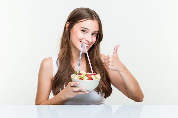 Mujer caucásica joven bebiendo un frutero con una pajita