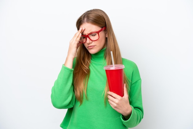 Mujer caucásica joven bebiendo refresco aislado sobre fondo blanco con dolor de cabeza