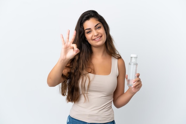 Mujer caucásica joven con una botella de agua aislada sobre fondo blanco feliz y contando tres con los dedos