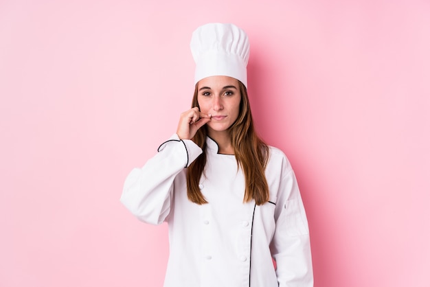 Mujer caucásica joven del cocinero aislada con los dedos en los labios que guardan un secreto.