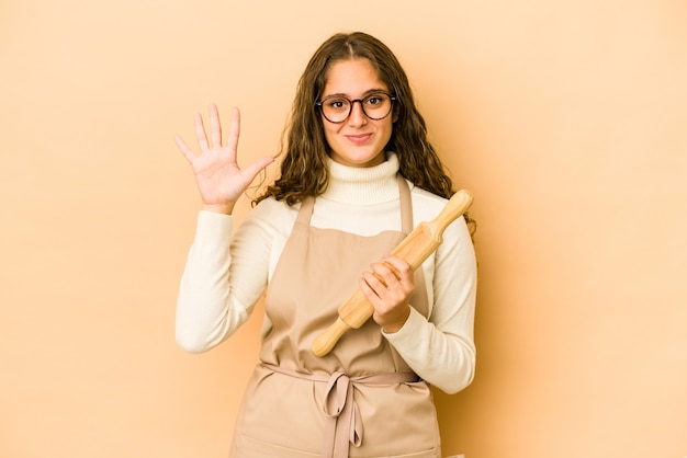 Mujer caucásica joven del cocinero aislada que sonríe alegre que muestra el número cinco con los dedos.