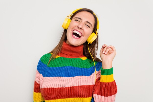 Mujer caucásica joven escuchando música con auriculares aislado sobre fondo blanco.