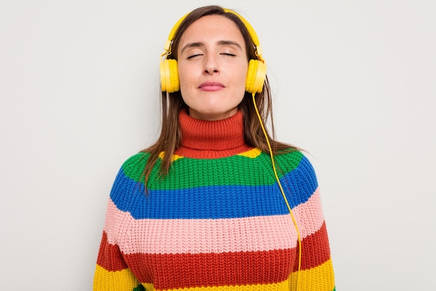 Mujer caucásica joven escuchando música con auriculares aislado sobre fondo blanco.