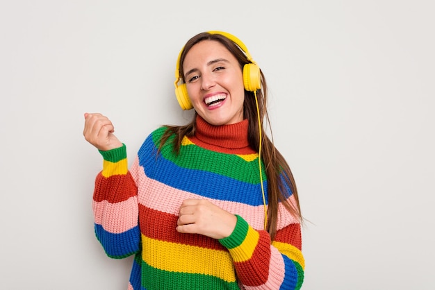 Mujer caucásica joven escuchando música con auriculares aislado sobre fondo blanco.