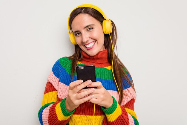 Mujer caucásica joven escuchando música con auriculares tocando su teléfono móvil