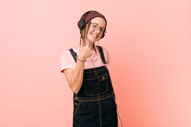 Mujer caucásica joven escuchando música sonriendo y levantando el pulgar