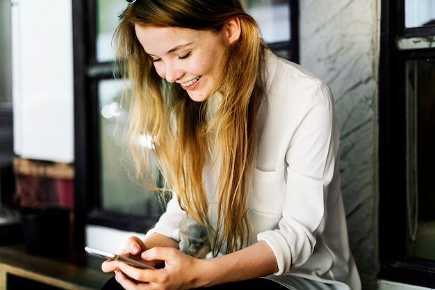 La mujer caucásica joven está utilizando el teléfono móvil