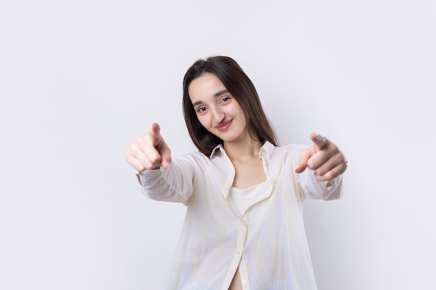 Mujer caucásica joven feliz en una camisa que señala los dedos lejos