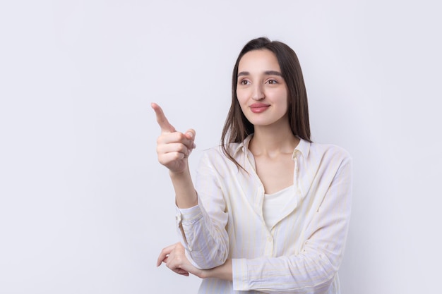 Mujer caucásica joven feliz en una camisa que señala los dedos lejos