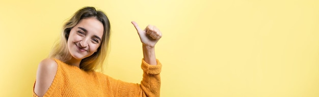 Mujer caucásica joven feliz en un suéter naranja haciendo señal de pulgar hacia arriba y sonriendo Buen trabajo y respetox9