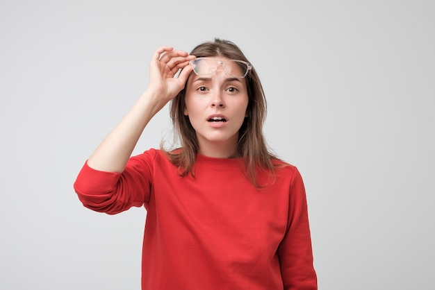 Mujer caucásica joven con gafas mirando a la cámara con duda y desconfianza