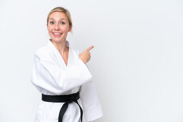 Mujer caucásica joven haciendo karate aislado sobre fondo blanco apuntando hacia un lado para presentar un producto