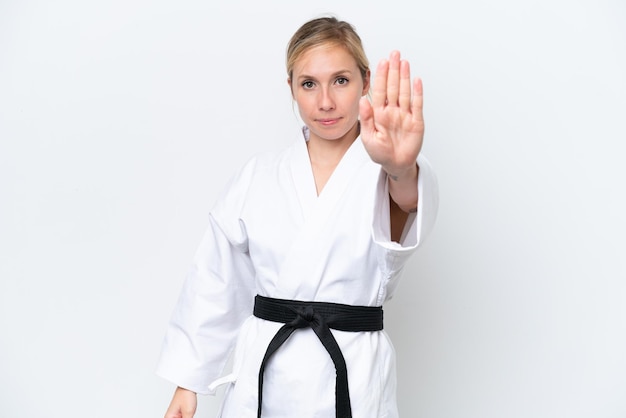 Mujer caucásica joven haciendo karate aislado sobre fondo blanco haciendo gesto de parada