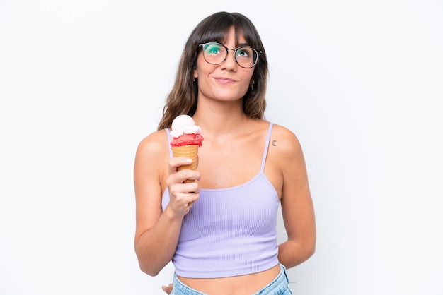 Mujer caucásica joven con un helado de cucurucho sobre fondo blanco aislado y mirando hacia arriba