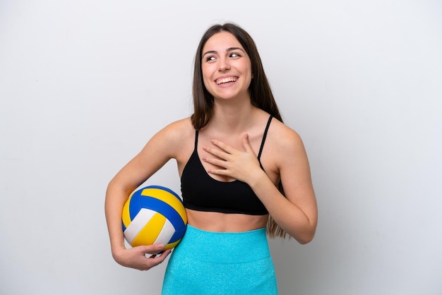 Mujer caucásica joven jugando voleibol aislado sobre fondo blanco sonriendo mucho