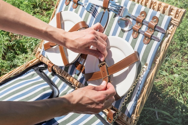 Mujer caucásica joven mano preparando cesta de picnic al aire libre lista para hacer un picnic