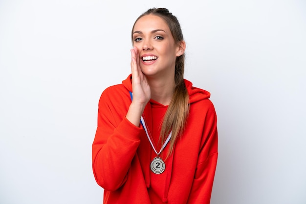 Mujer caucásica joven con medallas aisladas sobre fondo blanco gritando con la boca abierta