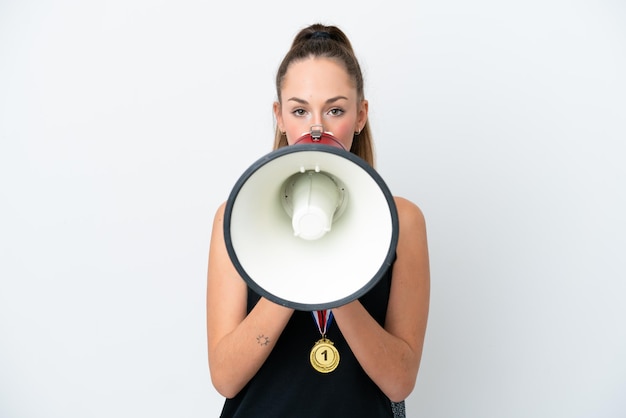 Mujer caucásica joven con medallas aislado sobre fondo blanco gritando a través de un megáfono