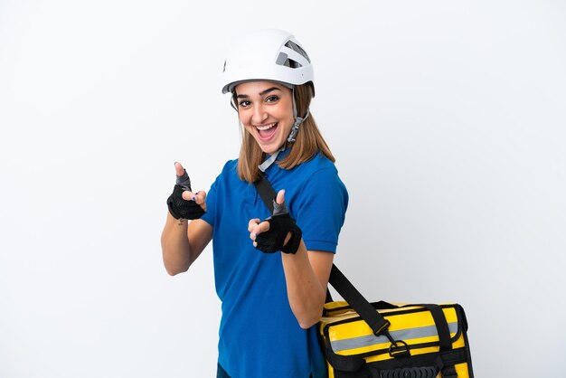 Mujer caucásica joven con mochila térmica aislada sobre fondo blanco apuntando al frente y sonriendo