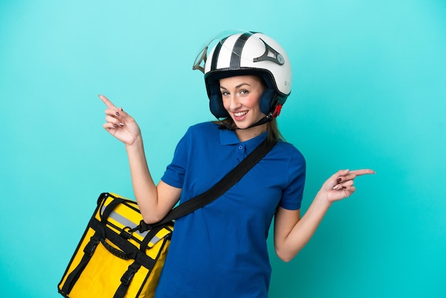 Mujer caucásica joven con mochila térmica aislada sobre fondo blanco señalando con el dedo a los laterales y feliz