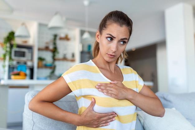 Mujer caucásica joven palpando su seno por sí misma que le preocupa el cáncer de mama Concepto de salud y cáncer de mama