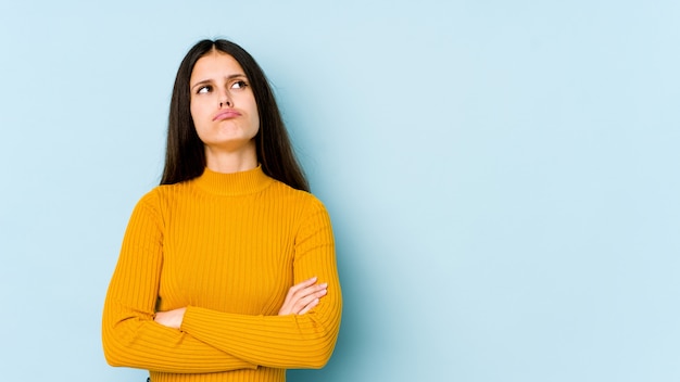 Mujer caucásica joven en la pared azul cansada de una tarea repetitiva.