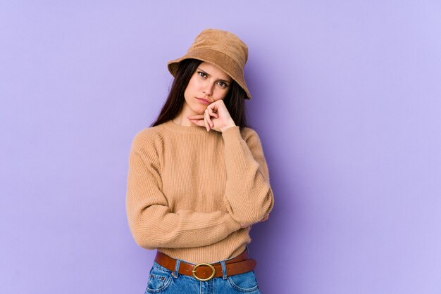 Mujer caucásica joven en la pared púrpura cansada de una tarea repetitiva.