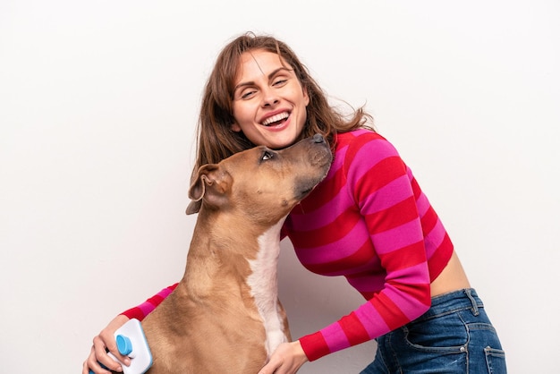 Foto mujer caucásica joven peinando a su perro aislado sobre fondo blanco.