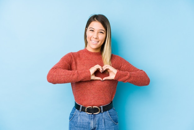 Foto mujer caucásica joven posando sonriendo y mostrando una forma de corazón con las manos.