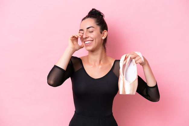 Mujer caucásica joven practicando ballet aislado sobre fondo rosa riendo