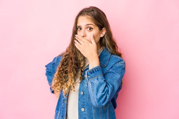 Mujer caucásica joven que cubre la boca con las manos mirando preocupado.