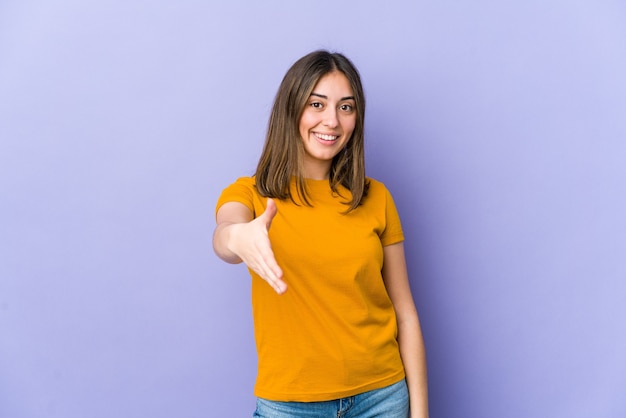 Mujer caucásica joven que estira la mano en gesto de saludo.