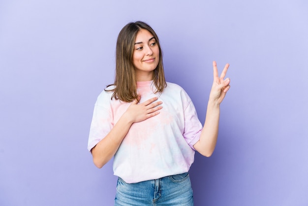 Mujer caucásica joven que hace un juramento, poniendo la mano en el pecho.