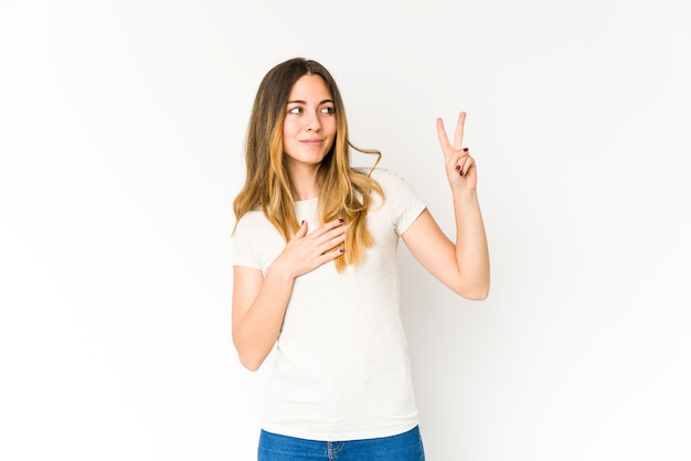 Mujer caucásica joven que hace un juramento, poniendo la mano en el pecho.