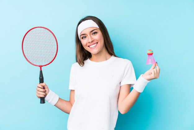 La mujer caucásica joven que jugaba a bádminton aisló feliz, sonriente y alegre.