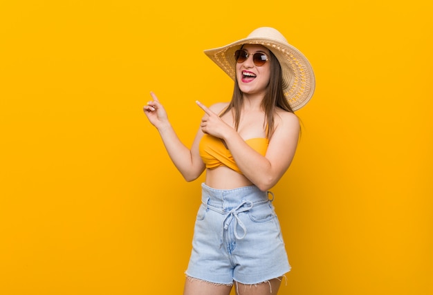 La mujer caucásica joven que llevaba un sombrero de paja, mirada del verano excitó sostener un espacio de la copia en la palma.