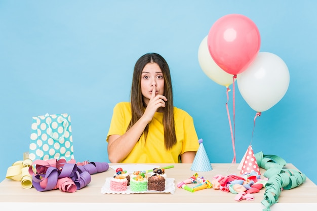 Mujer caucásica joven que organiza un cumpleaños que guarda un secreto o pide silencio.