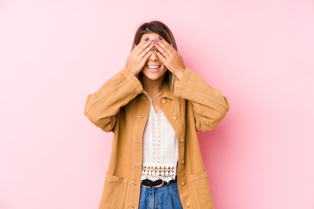 La mujer caucásica joven que presenta aislada cubre ojos con las manos, sonrisas en general esperando una sorpresa.