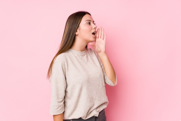 Mujer caucásica joven que presenta gritando y sosteniendo la palma cerca de la boca abierta.