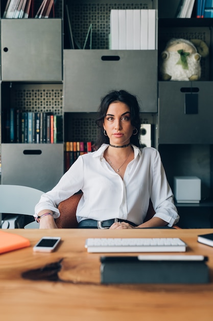 Foto mujer caucásica joven que presenta en oficina moderna y que mira la cámara