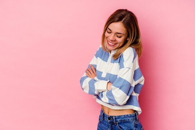 Mujer caucásica joven que sonríe confiada con los brazos cruzados.