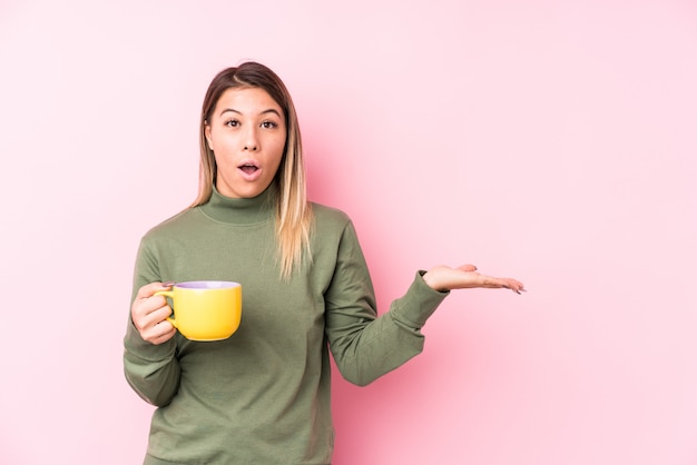 La mujer caucásica joven que sostenía un café impresionó llevar a cabo el espacio de la copia en la palma.